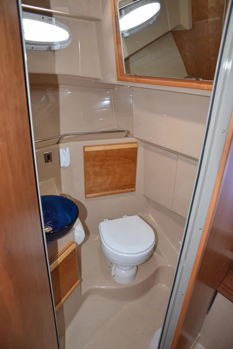 Slide: The Image of 2016 Cutwater C26 boat bathroom with toilet, sink, and wooden cabinetry. - 13