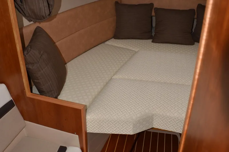 Slide: The Image of 2016 Cutwater C26 cabin interior with cozy bed and brown cushions. - 16