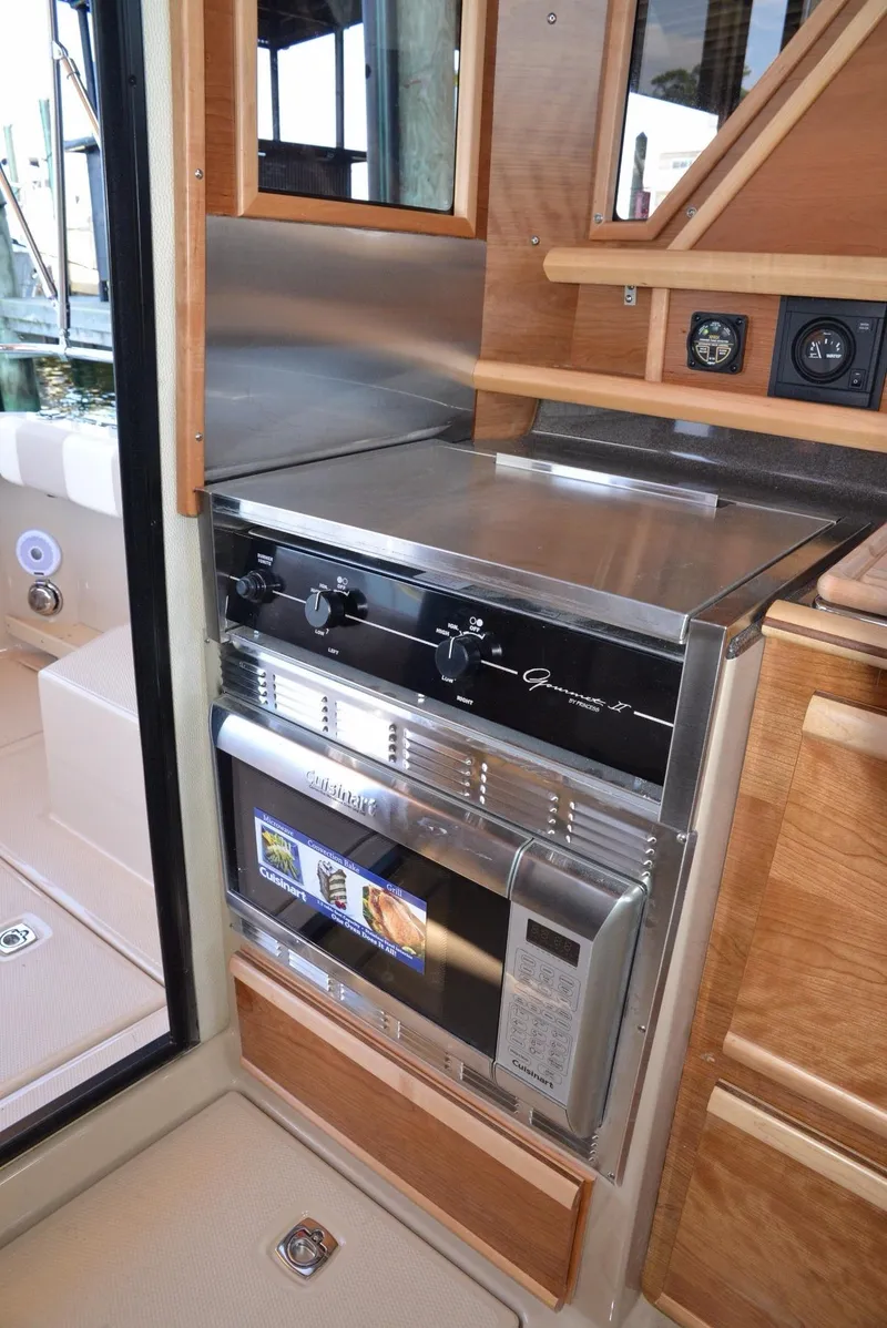 Slide: The Image of 2016 Cutwater C26 interior kitchen with stove and microwave, featuring wood cabinetry. - 7