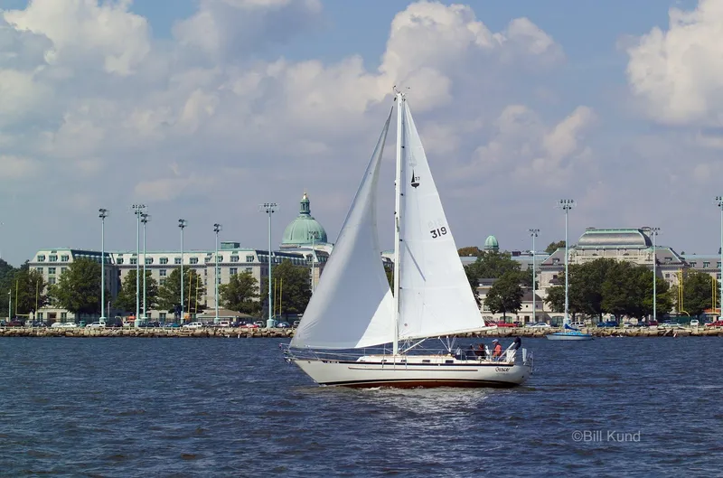 Slide: The Image of Sailboat Pacific Seacraft 37, 2025 model, cruising on a sunny day near a coastal cityscape. - 2