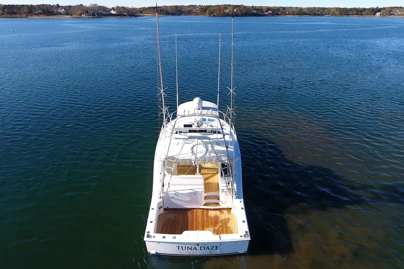 Slide: The Image of 2004 Cabo Express boat on calm water, rear view with fishing rods. - 15