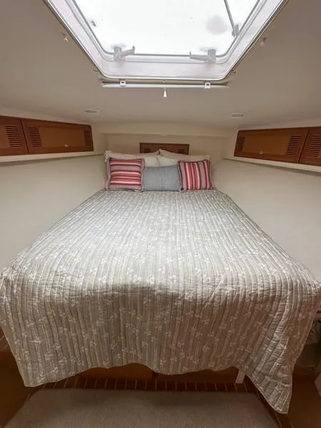 Slide: The Image of 2004 Cabo Express boat cabin with cozy bed and striped pillows. - 43