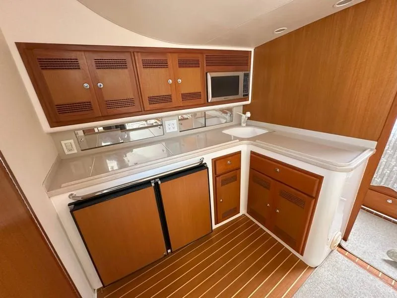 Slide: The Image of 2004 Cabo Express boat kitchen with wood cabinets, microwave, and compact fridge. - 47