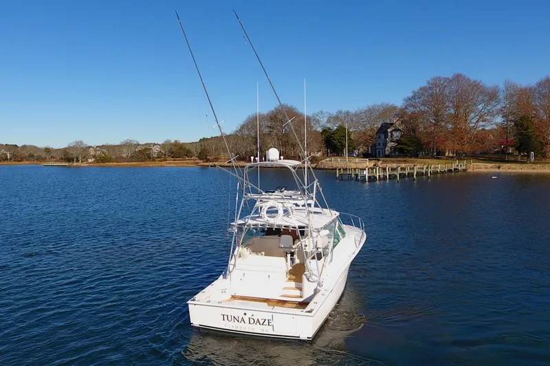 Slide: The Image of 2004 Cabo Express boat "Tuna Daze" on calm water near a wooded shoreline. - 4
