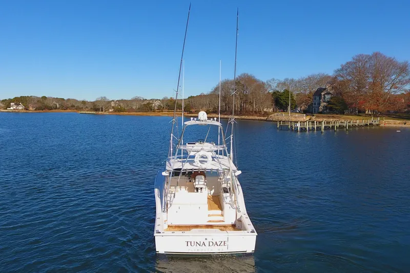 Slide: The Image of 2004 Cabo Express boat named "Tuna Daze" on a calm lake with a scenic shoreline. - 5