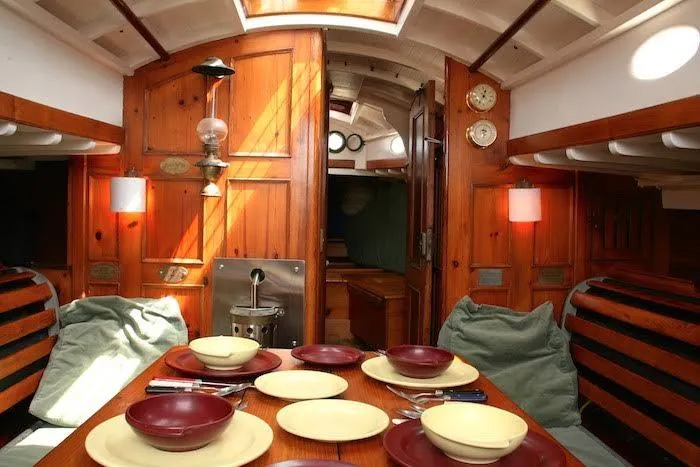 Slide: The Image of Interior of a 1958 Concordia Yawl sailboat with a wooden dining area. - 19