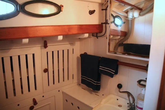 Slide: The Image of 1958 Concordia Yawl bathroom with wooden cabinets, mirror, and nautical decor. - 5