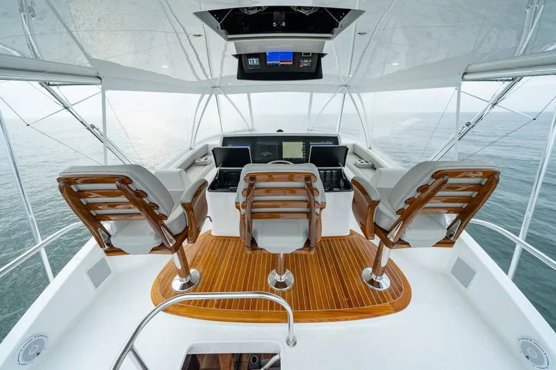 Slide: The Image of 2024 Viking 82 Convertible yacht helm with three captain's chairs and advanced navigation system. - 9