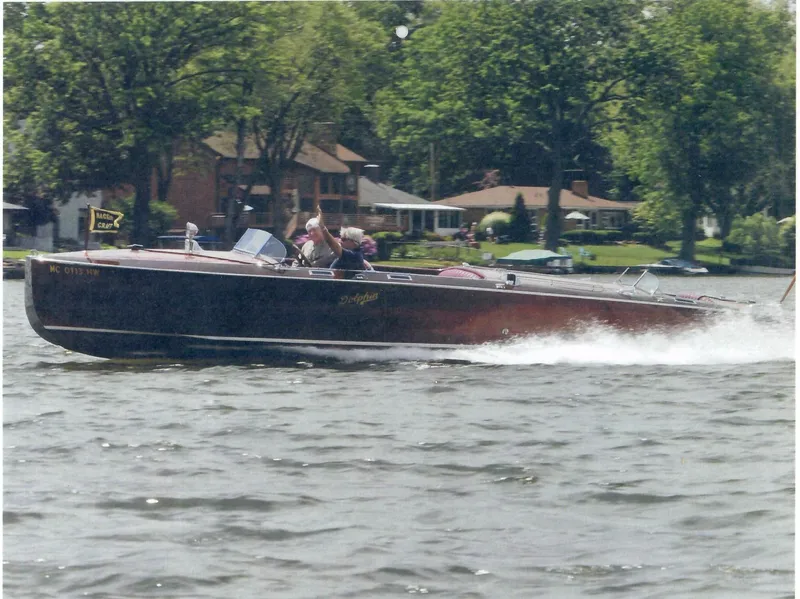Slide: The Image of 1928 Hacker-Craft Dolphin boat cruising on a lake with houses and trees in the background. - 20
