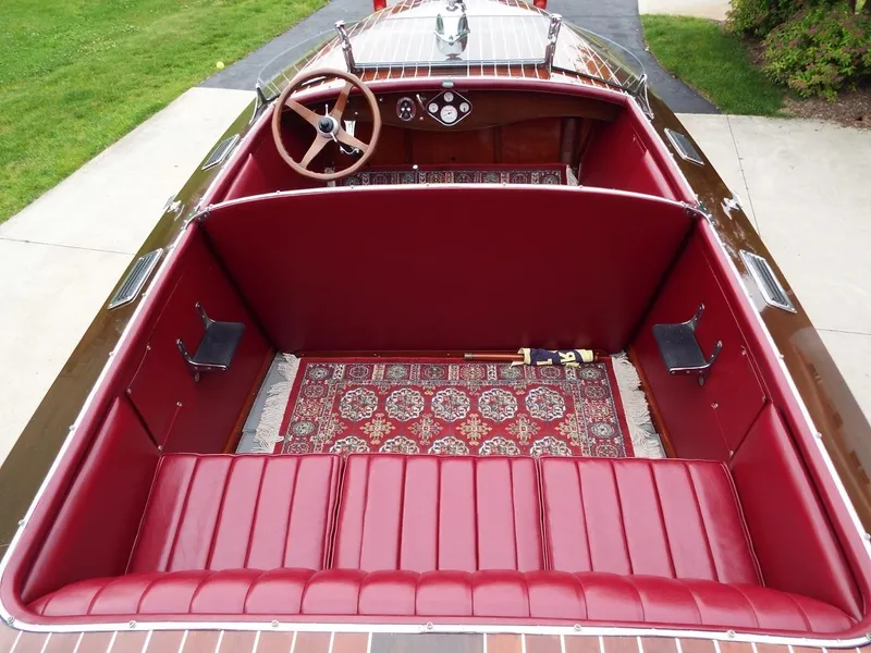 Slide: The Image of 1928 Hacker-Craft Dolphin boat interior with red leather seats and wooden steering wheel. - 8