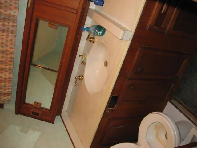 Slide: The Image of 1984 Chris-Craft Constellation bathroom with wooden cabinets, sink, and toilet. - 13