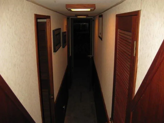 Slide: The Image of Narrow hallway inside a 1984 Chris-Craft Constellation boat, featuring wooden doors and paneling. - 19