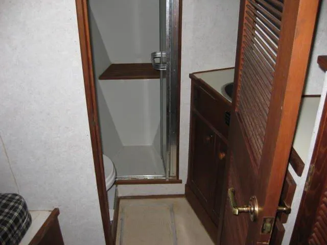 Slide: The Image of 1984 Chris-Craft Constellation bathroom with shower, wooden cabinetry, and compact design. - 21