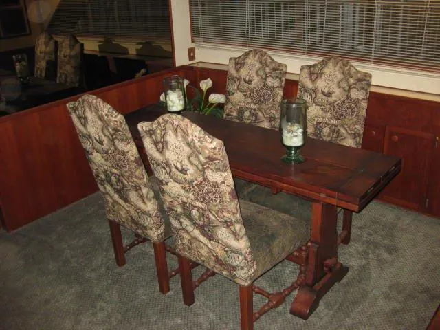 Slide: The Image of Dining area inside 1984 Chris-Craft Constellation with patterned chairs and wooden table. - 26