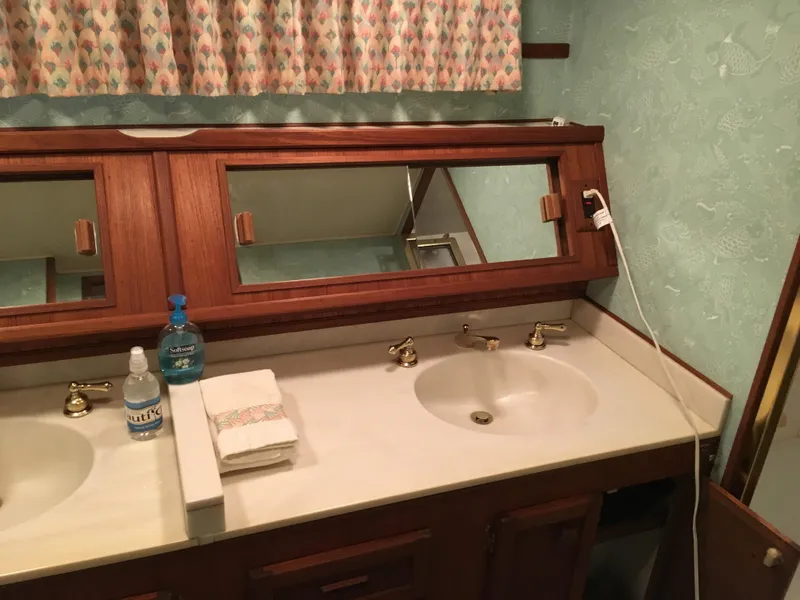 Slide: The Image of 1984 Chris-Craft Constellation bathroom with dual sinks, wooden cabinetry, and decorative curtains. - 45