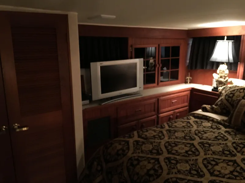 Slide: The Image of Luxurious 1984 Chris-Craft Constellation cabin interior with TV, wooden cabinetry, and elegant bedding. - 48