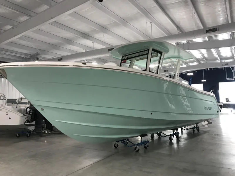 Slide: The Image of 2024 Robalo R302 boat in a showroom, mint green hull, side view. - 0
