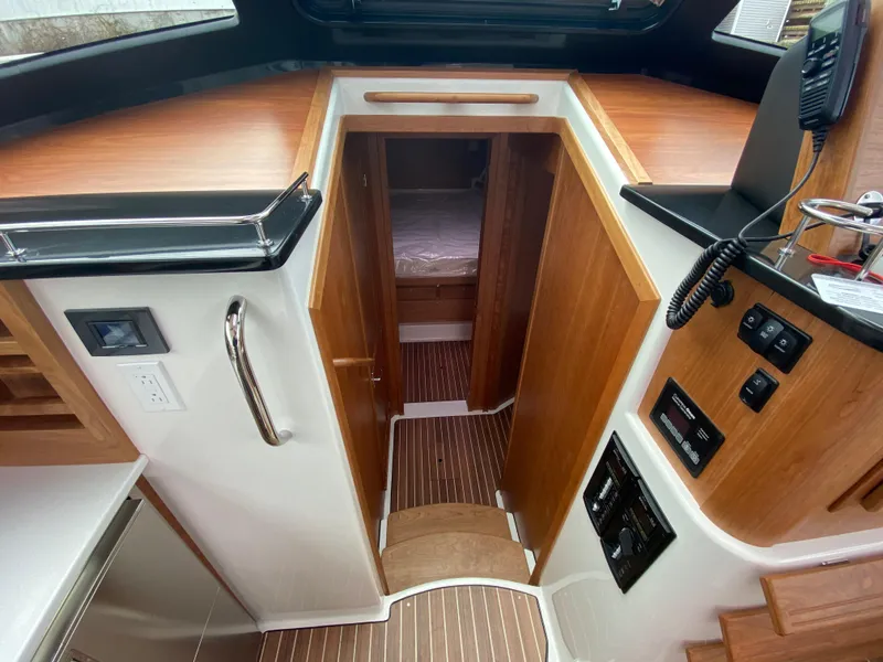 Slide: The Image of 2025 Back Cove 37 Hardtop Express kitchen with wood cabinetry, stove, microwave, and stainless steel appliances. - 9