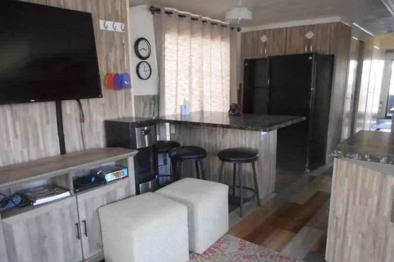 Slide: The Image of Modern houseboat interior with kitchen, bar stools, and wall-mounted TV, Stardust Cruisers 2000 model. - 5