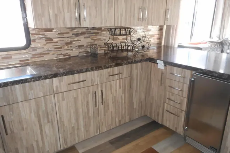 Slide: The Image of Modern kitchen in 2000 Stardust Cruisers houseboat with wood cabinets and stone backsplash. - 7