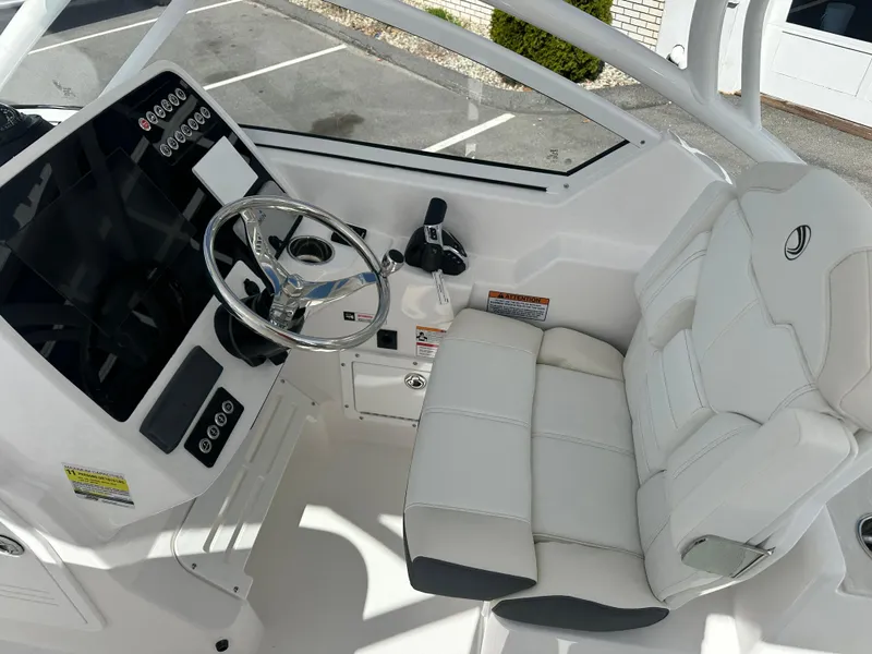 Slide: The Image of 2025 Edgewater 248CX Crossover boat cockpit with steering wheel and comfortable seating. - 23