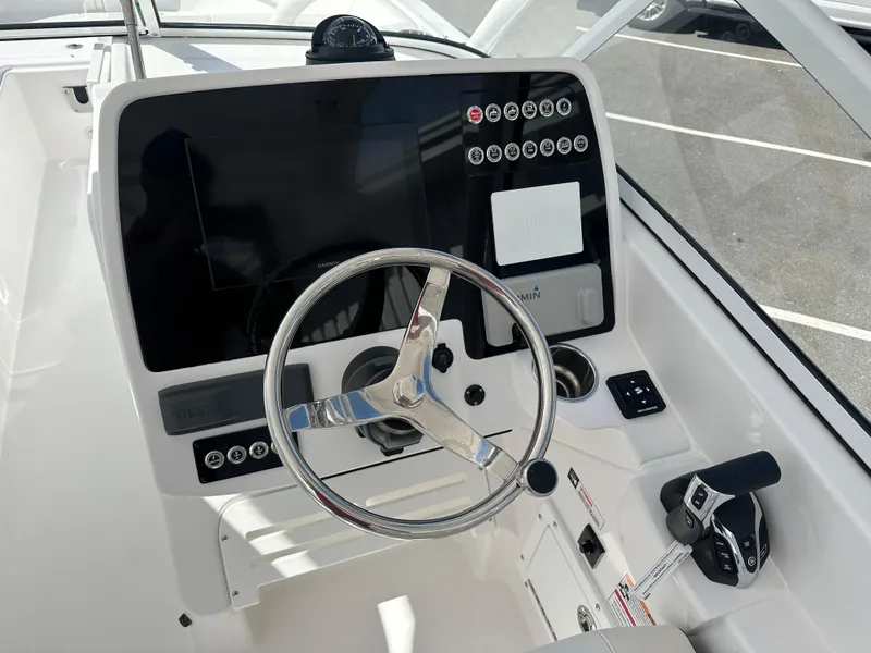 Slide: The Image of 2025 Edgewater 248CX Crossover boat cockpit with steering wheel and white seating. - 24