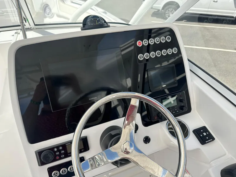 Slide: The Image of 2025 Edgewater 248CX Crossover boat dashboard with steering wheel and control panel. - 25