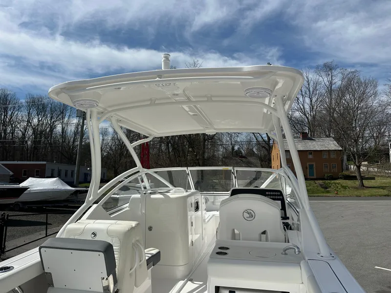 Slide: The Image of 2025 Edgewater 248CX Crossover boat interior with seating and storage, docked outdoors. - 8