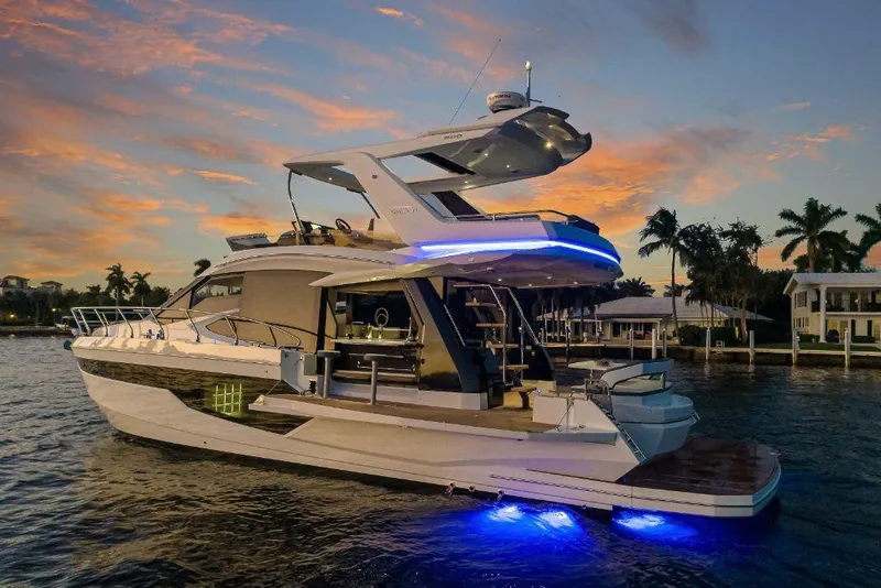 Slide: The Image of 2023 Galeon 500 Fly yacht at sunset with blue underwater lights. - 2