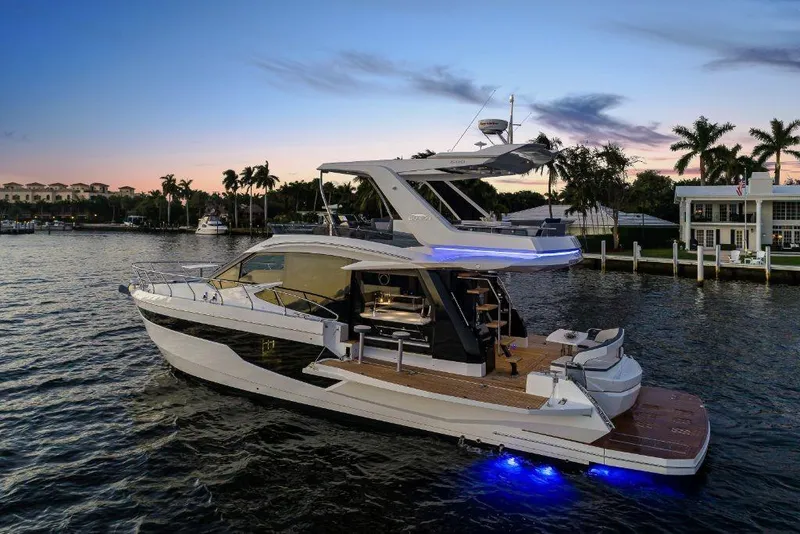 Slide: The Image of 2023 Galeon 500 Fly yacht at sunset with blue underwater lights. - 6