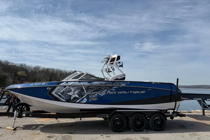 The Image of 2015 Nautique Super Air Nautique G25 boat on trailer by a lake. - 0