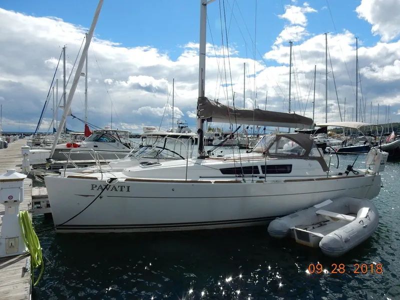 The Image of 2013 Jeanneau Sun Odyssey 33i sailboat docked at marina under cloudy sky. - 0