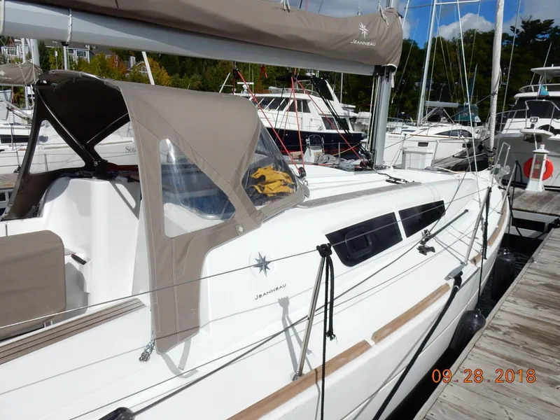 Slide: The Image of 2013 Jeanneau Sun Odyssey 33i sailboat docked at marina, featuring beige canopy. - 11