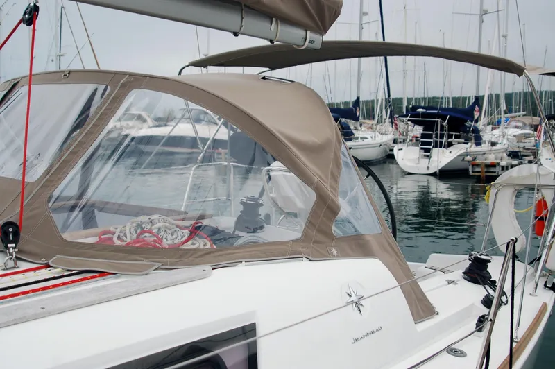 Slide: The Image of 2013 Jeanneau Sun Odyssey 33i sailboat docked in marina, featuring beige canopy. - 12