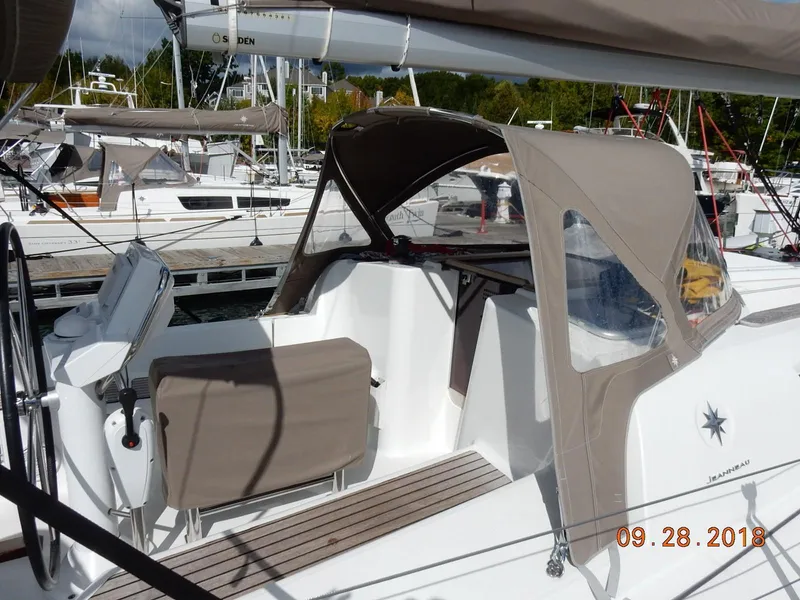 Slide: The Image of 2013 Jeanneau Sun Odyssey 33i sailboat docked, featuring a beige canopy and spacious cockpit. - 14