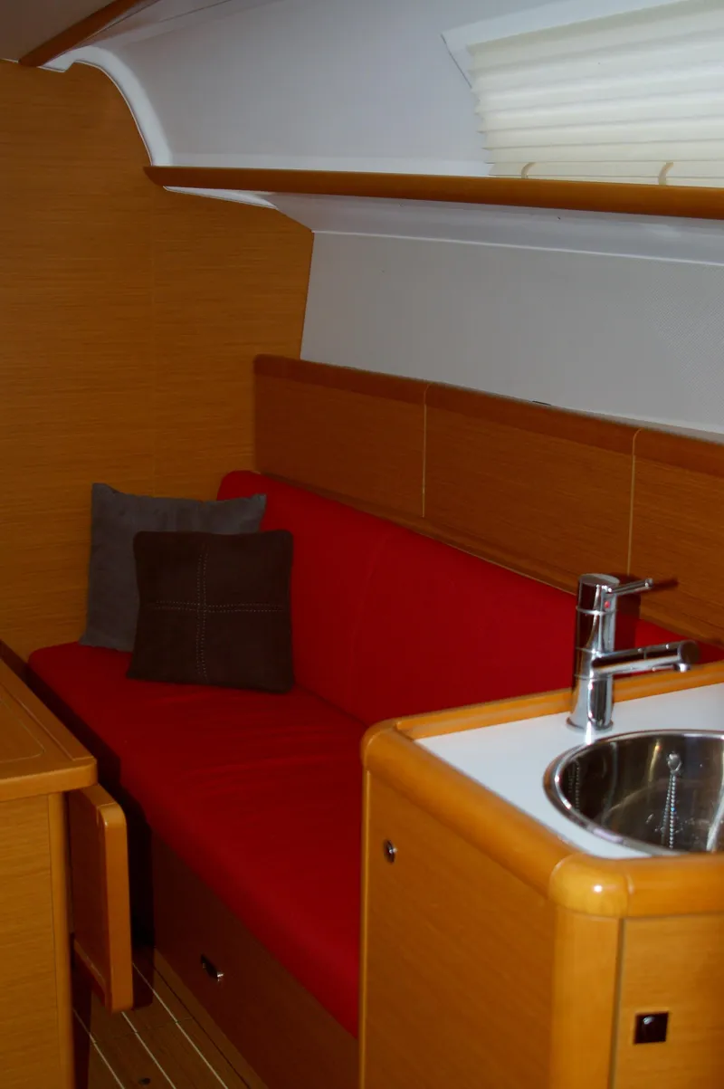 Slide: The Image of Interior of 2013 Jeanneau Sun Odyssey 33i with red seating and compact kitchenette. - 19