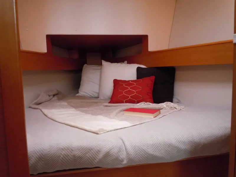 Slide: The Image of Cozy cabin interior of 2013 Jeanneau Sun Odyssey 33i with pillows and a book. - 2