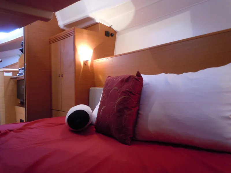 Slide: The Image of Cozy cabin interior of 2013 Jeanneau Sun Odyssey 33i with red bedding and wooden accents. - 25