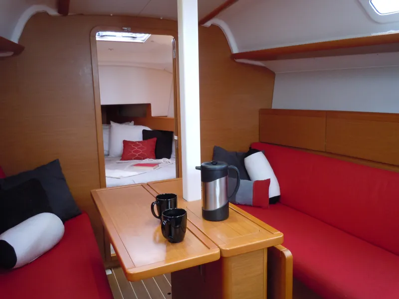 Slide: The Image of Interior of 2013 Jeanneau Sun Odyssey 33i sailboat with red seating and wooden table. - 26