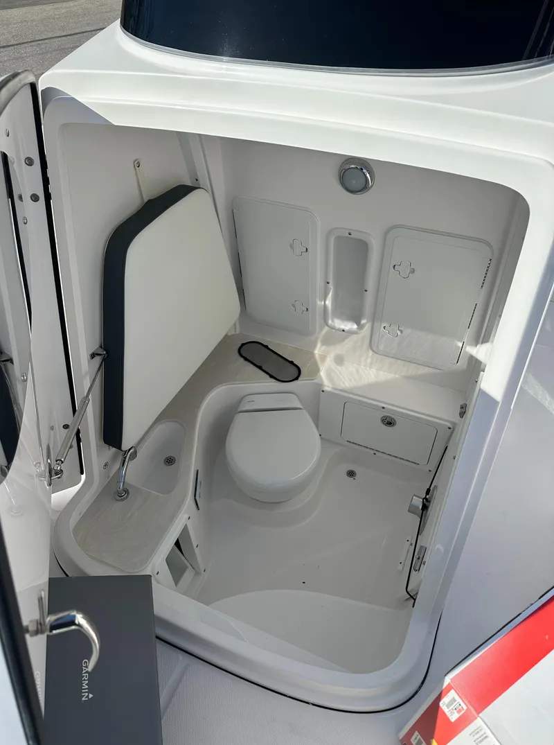 Slide: The Image of 2025 Edgewater 262 Center Console boat interior with compact marine toilet and storage compartments. - 39