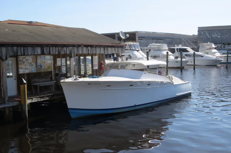 Slide: The Image of 1953 Rybovich Express boat docked at a marina, surrounded by other vessels. - 18