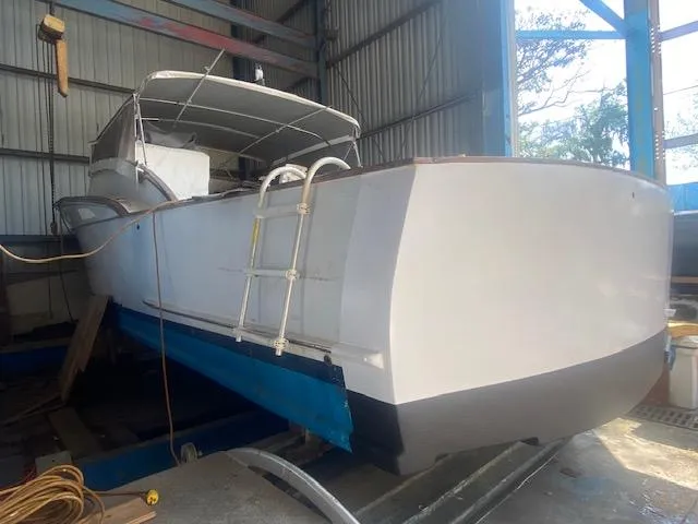 Slide: The Image of 1953 Rybovich Express boat in a shed, featuring a white hull and blue bottom. - 22