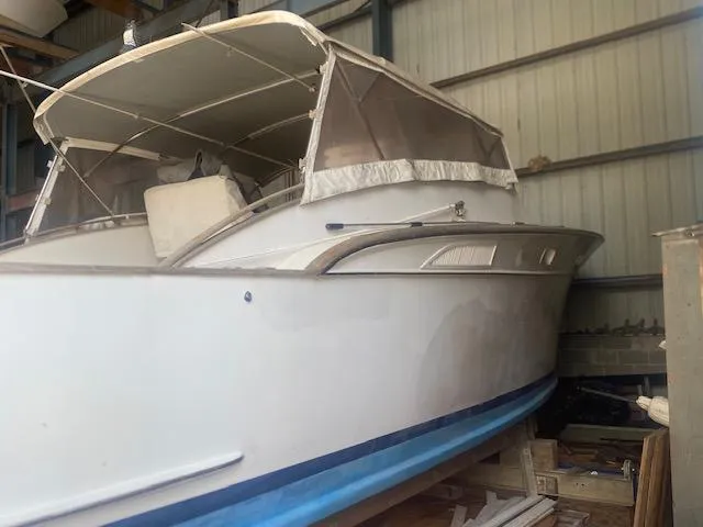 Slide: The Image of 1953 Rybovich Express boat in storage, featuring a white hull and canopy. - 24