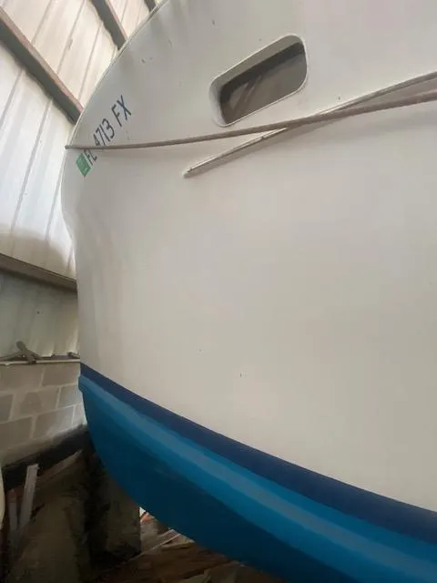 Slide: The Image of 1953 Rybovich Express boat with white hull and blue stripe in storage. - 26