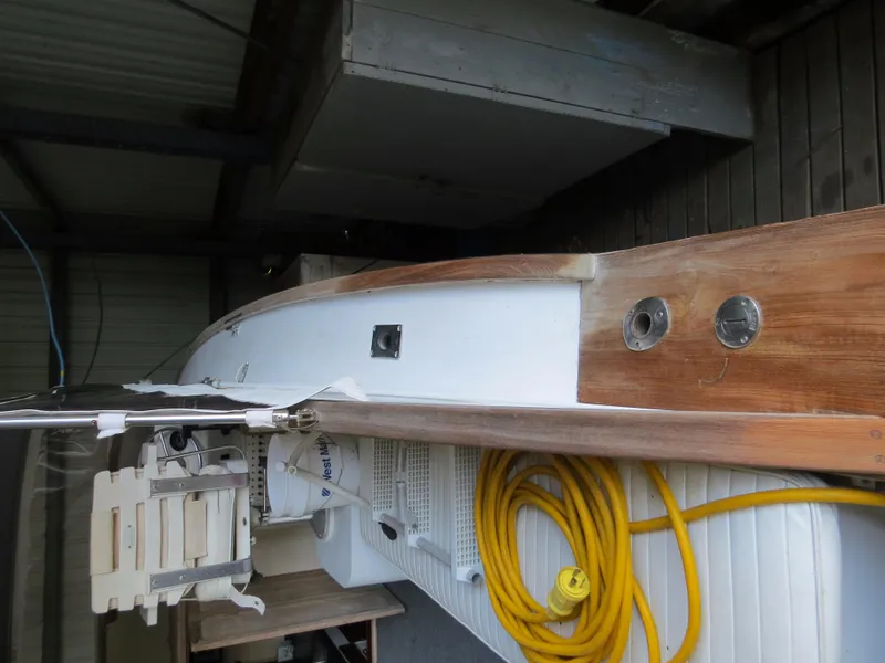 Slide: The Image of 1953 Rybovich Express boat with wooden deck and yellow hose in storage. - 6
