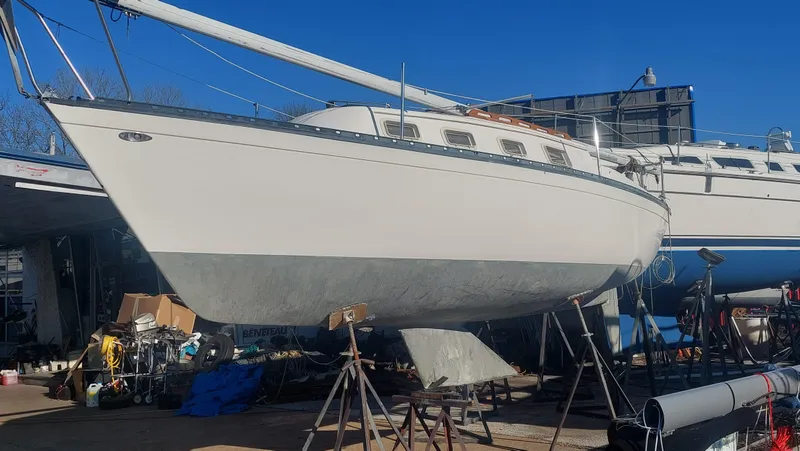 Slide: The Image of 1982 Hunter 25 sailboat on stands in a boatyard, clear blue sky. - 21