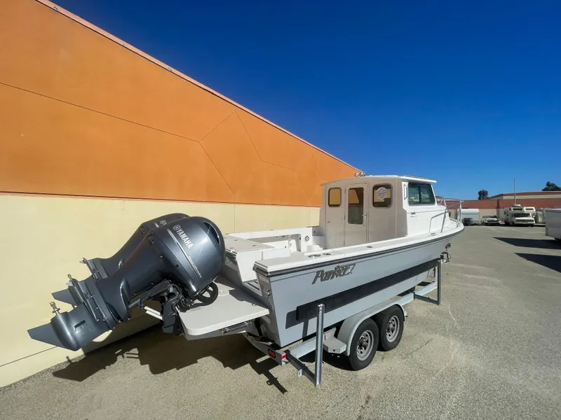 Slide: The Image of 2023 Parker 2520 XLD Sport Cabin boat on trailer, parked outdoors under clear blue sky. - 9