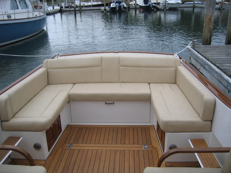 Slide: The Image of 2026 CH Marine Shelter Island Runabout with beige seating and wooden deck at a marina. - 11