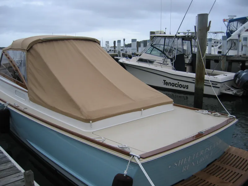 Slide: The Image of 2026 CH Marine Shelter Island Runabout docked, featuring a beige cover and blue hull. - 12