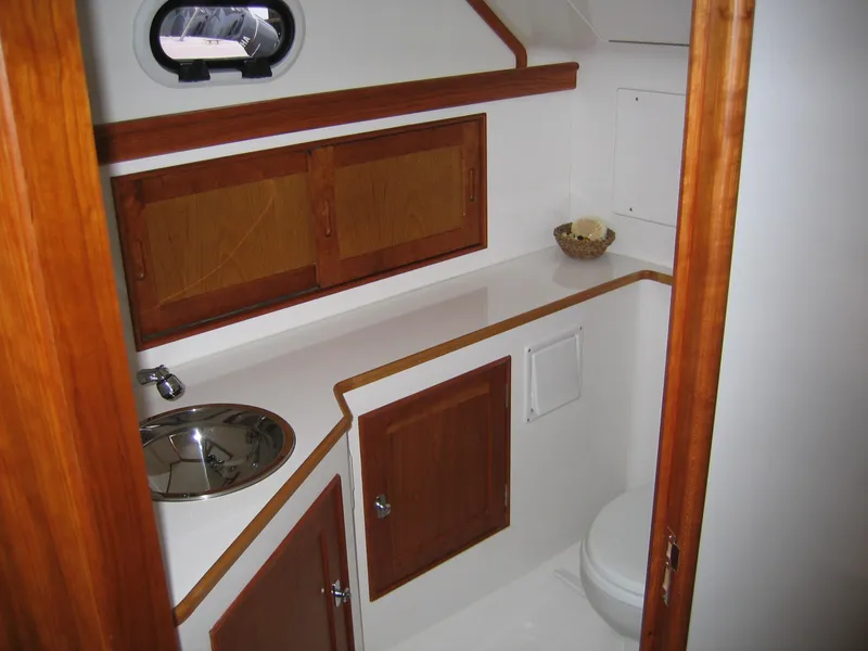 Slide: The Image of 2026 CH Marine Shelter Island Runabout interior with wooden cabinets and compact bathroom. - 6